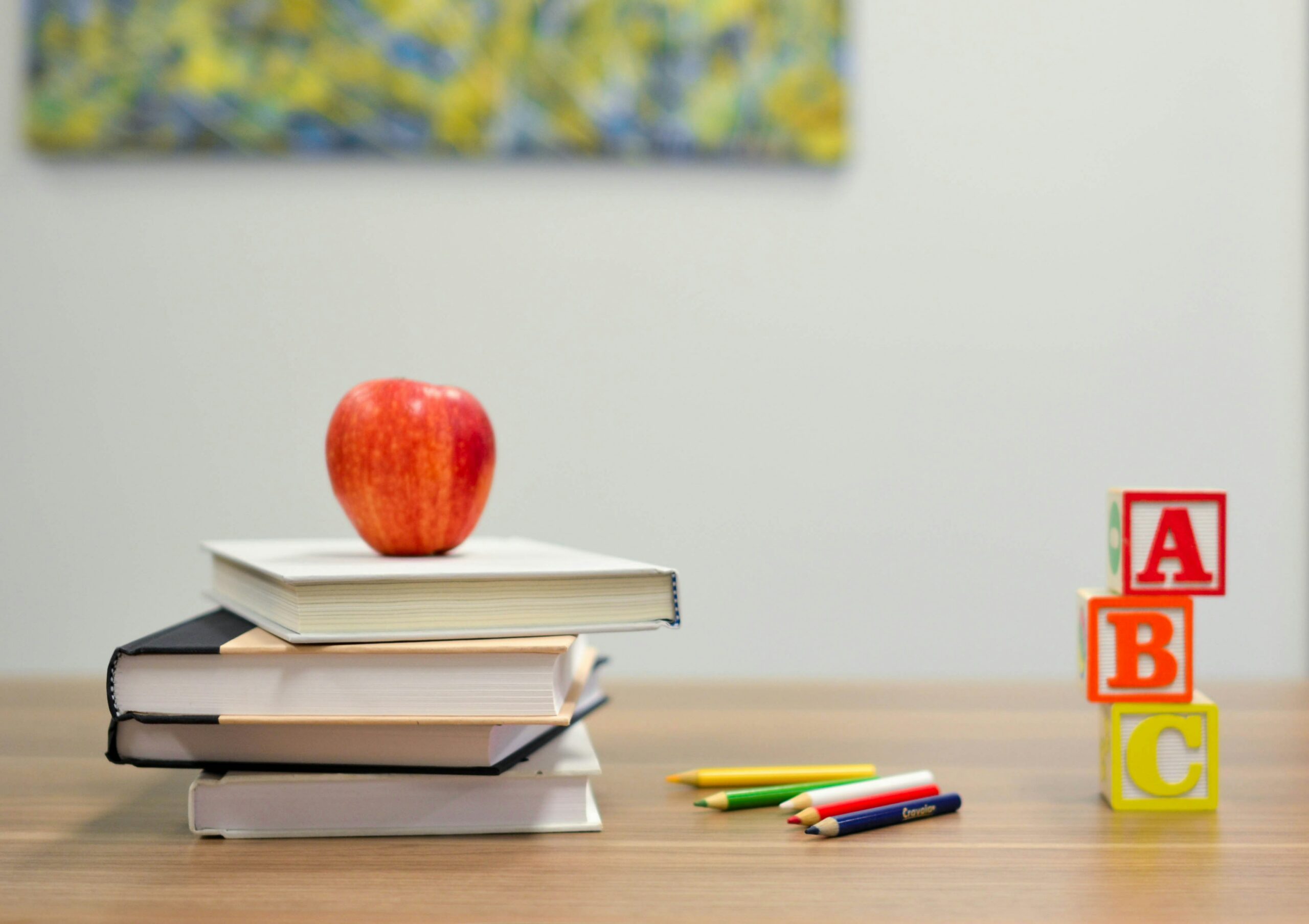 photo of stack of books, apple and blocks