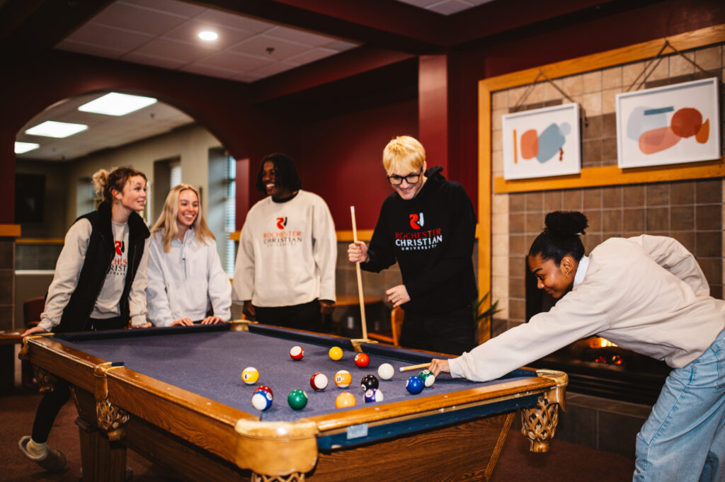 student playing pool inside residence hall